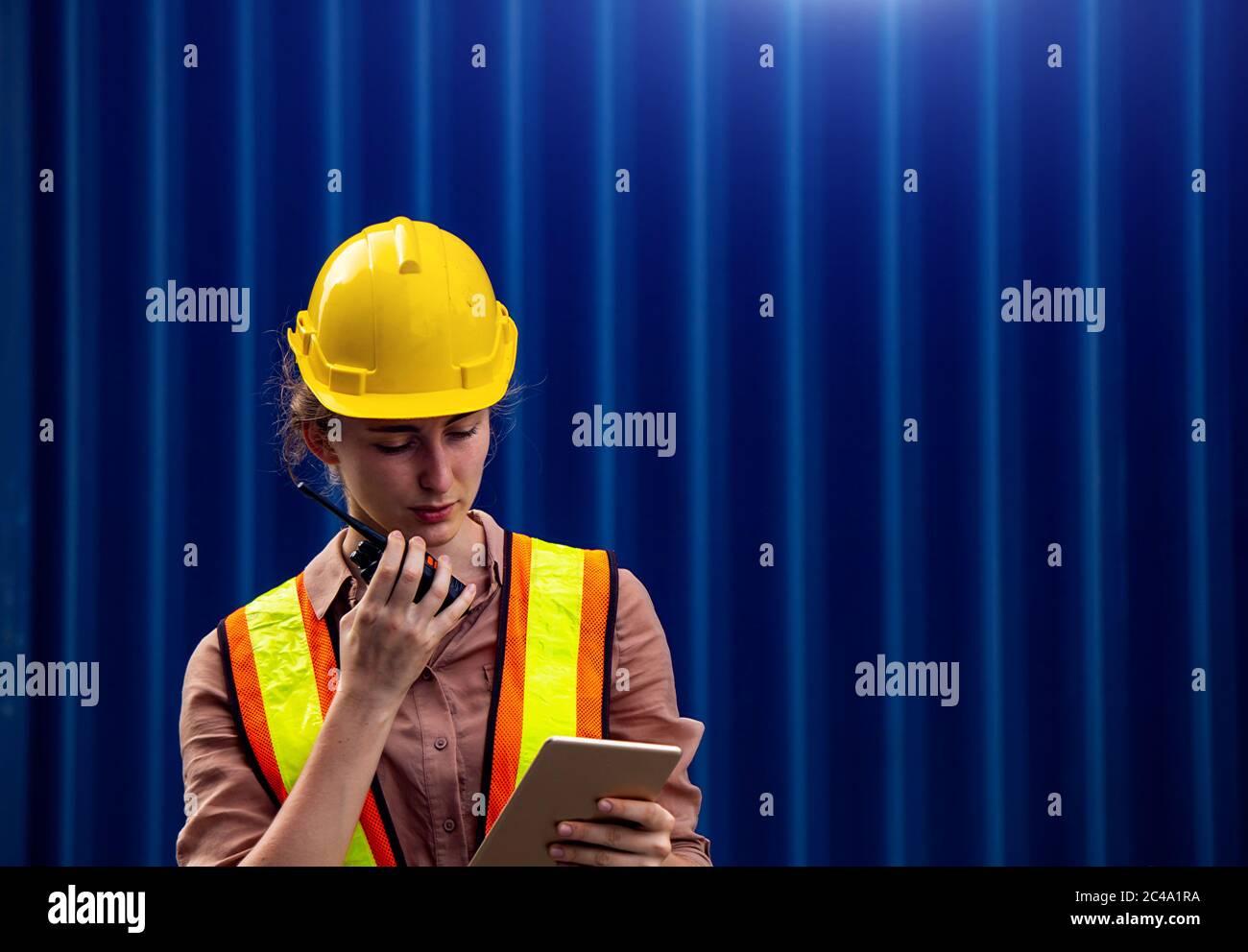 Female foreman is using walkie talkie and computer tablet to control work in industrial business Stock Photo