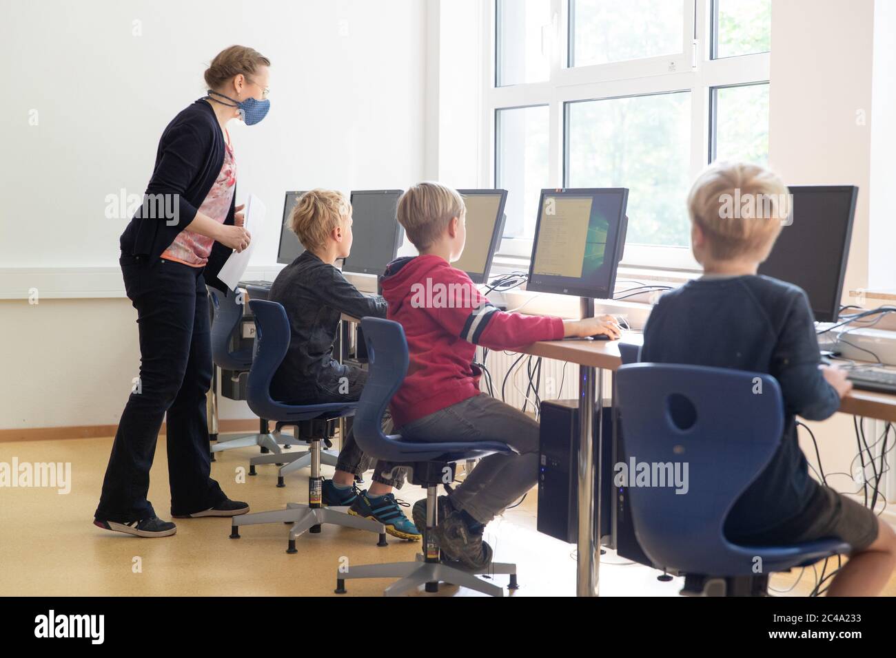 19 June 2020, Lower Saxony, Osnabrück: Teacher Dagmar Kreiling teaches  primary school pupils sitting in a computer room with computers. Due to the  corona regulations, special hygiene measures apply. Furthermore, the pupils