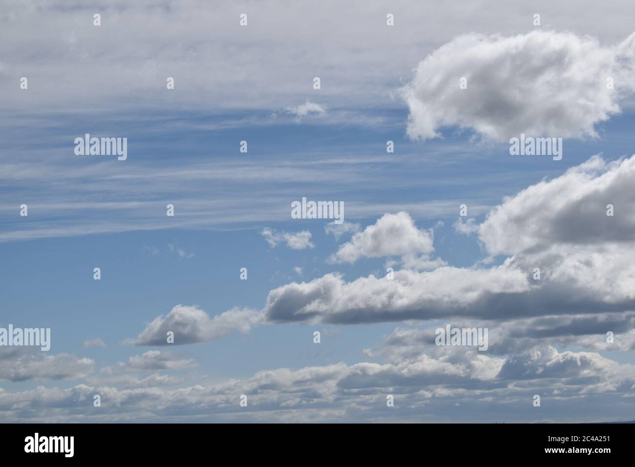 Various white and grey cloud formations against a blue sky. Stock Photo