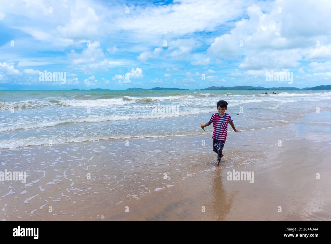 Asian kid enjoy playing in the sea and enjoying life during the summer holidays on the Phala Beach, Ban Chang District, Rayong, Thailand. Stock Photo