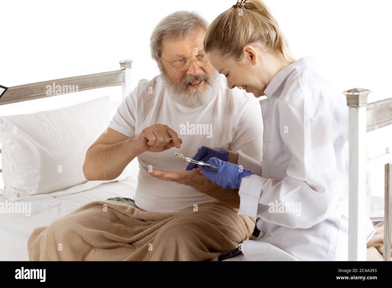 Elderly old man recovering in hospital bed isolated on white background. Getting care and
