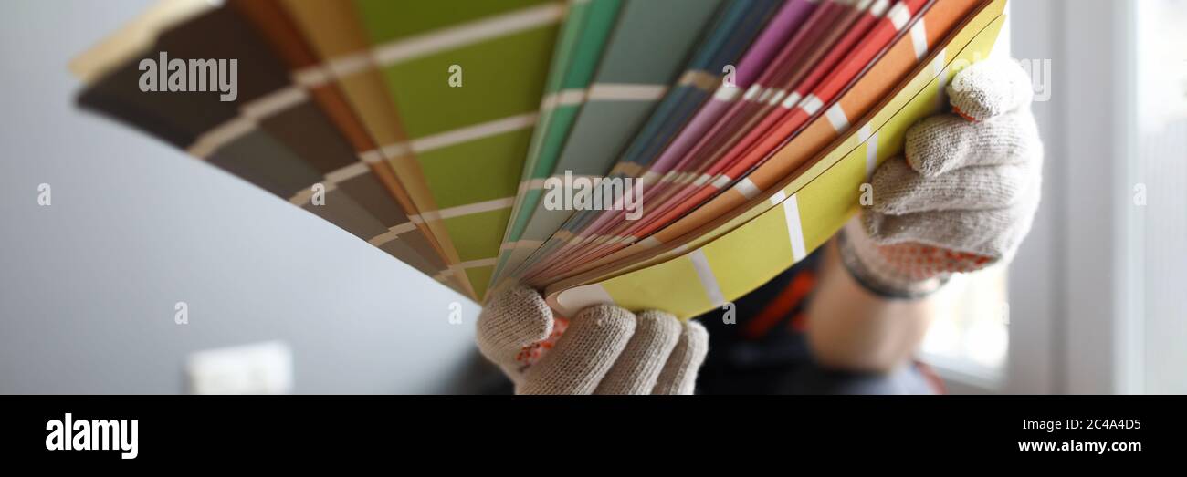 Builder in gloves shows color samples for repair Stock Photo