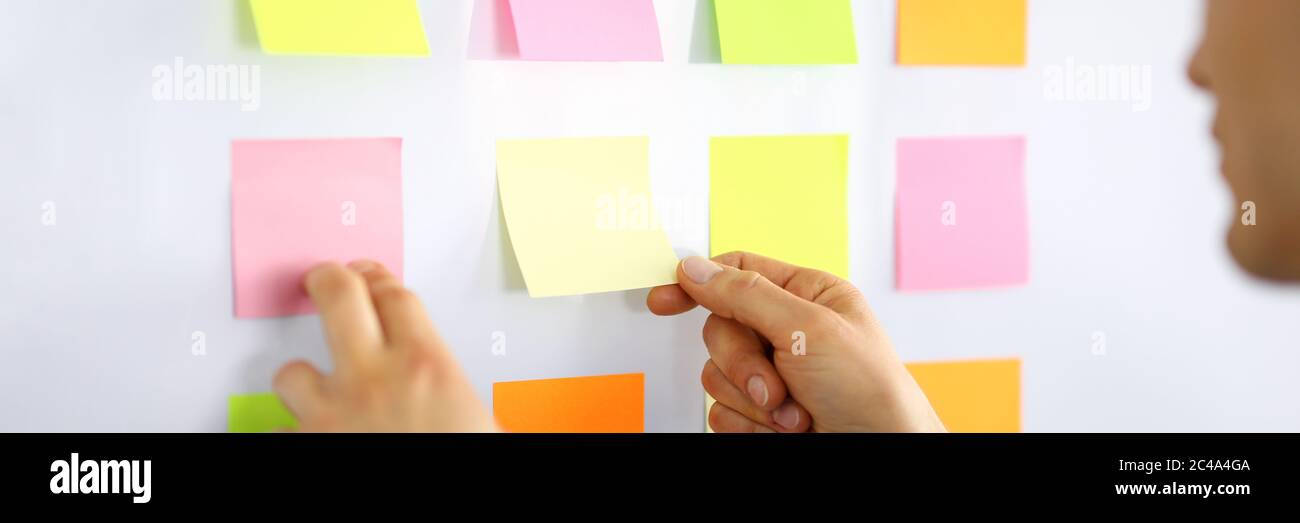 Male manager glues small notes on the wall Stock Photo