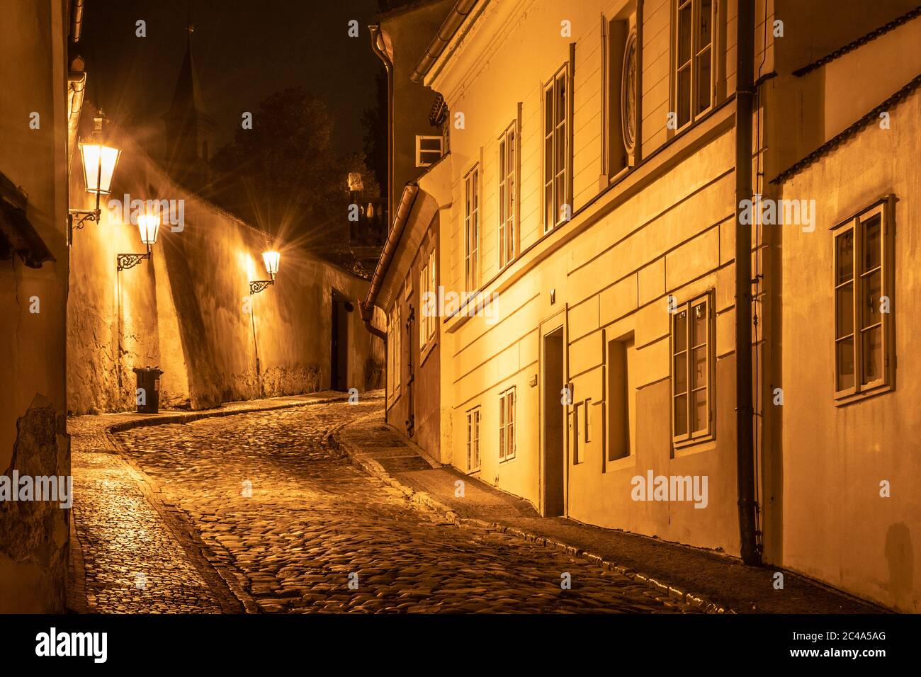Narrow cobbled street in old medieval town with illuminated houses by ...