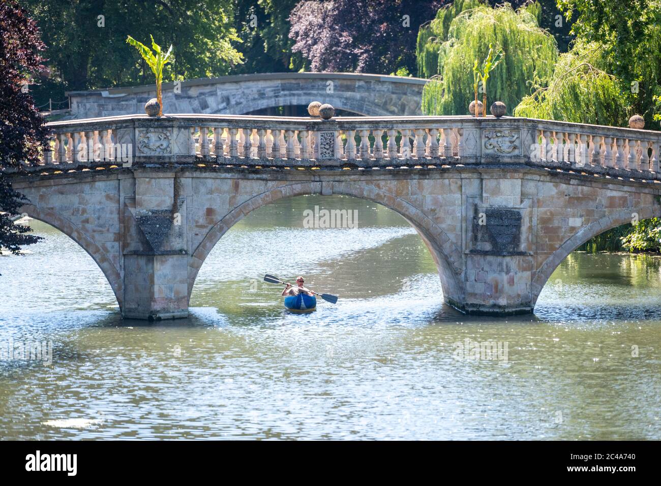 Cambridge, UK. 25th June, 2020. A man enjoys the heatwave in a kayak on the River Cam by Clare Bridge as temperatures rise above 30 degrees centigrade. The river is very quiet due to the shutting of most punting companies during the coronavirus lockdown. There are also warnings of high ultraviolet violet rays in the less polluted summer weather. Credit: Julian Eales/Alamy Live News Stock Photo