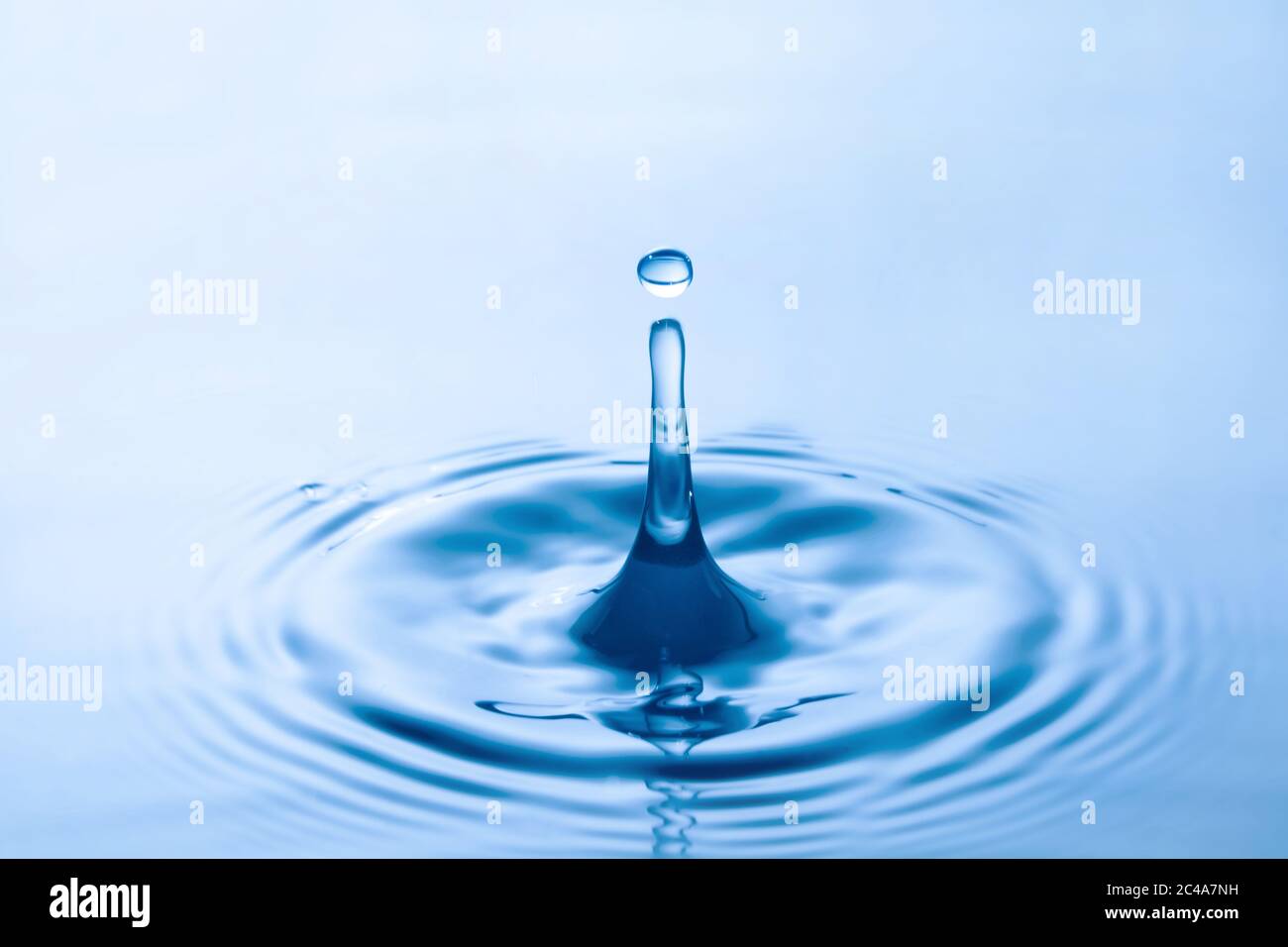 Water droplet falling impact with water surface. causing rings on water surface. Stock Photo