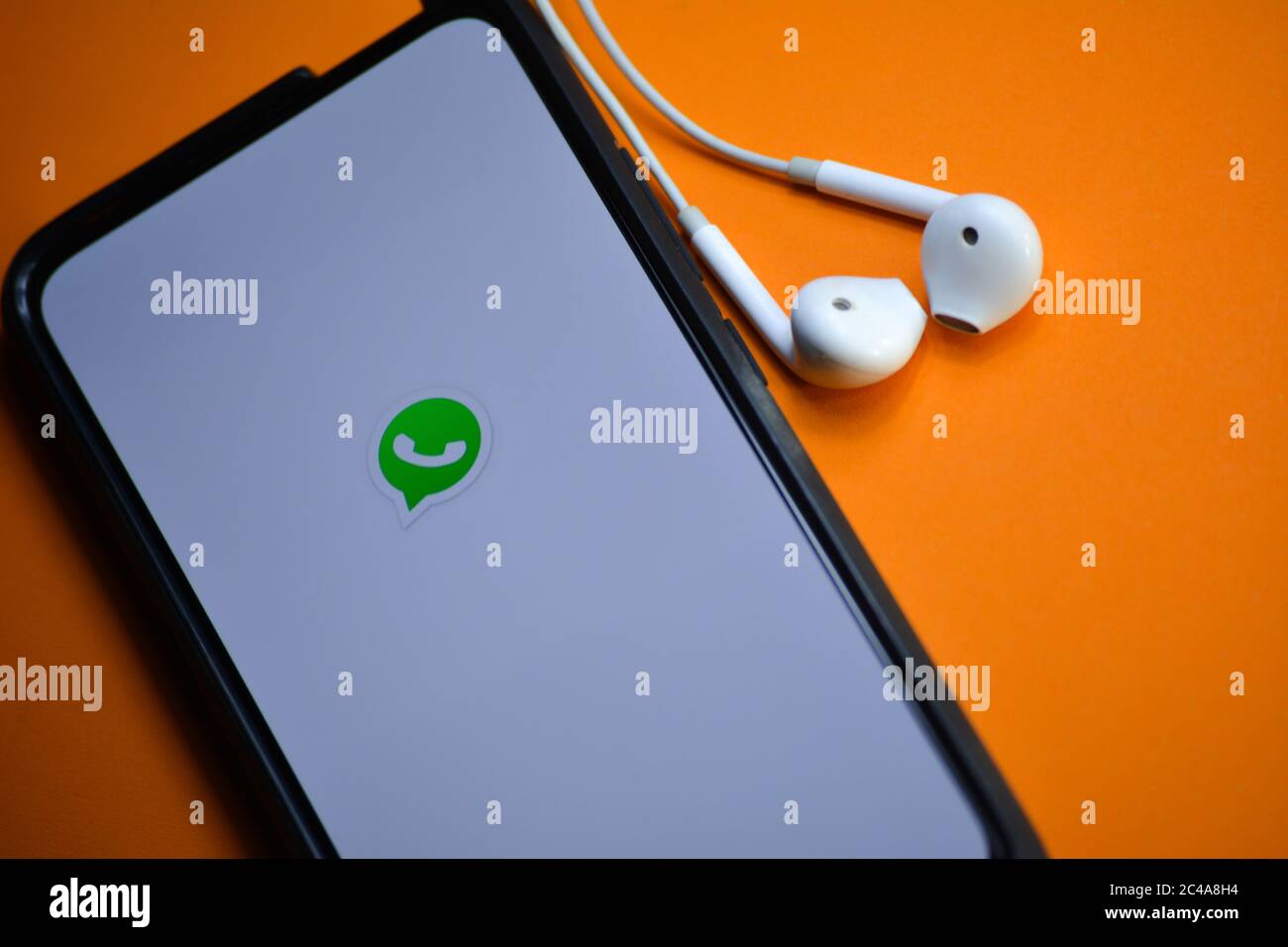 TIKAMGARH, MADHYA PRADESH, INDIA - DECEMBER 17, 2019: WhatsApp logo on smartphone screen with earphones. Stock Photo