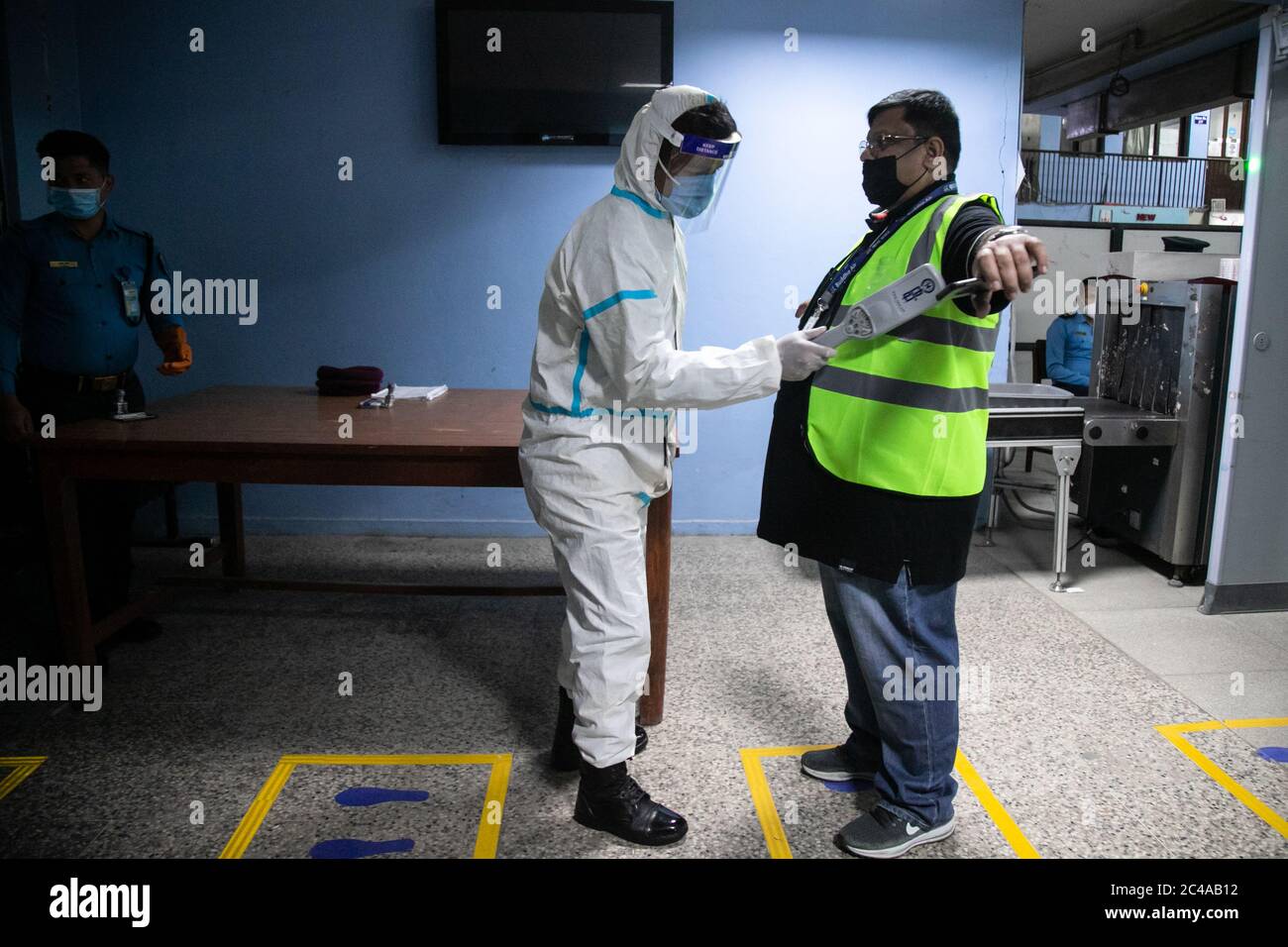 A security person wearing protective gear searches a passenger at Tribhuvan International airport during a mock safety drill to make necessary preparations for the resumption of domestic and international flights.Commercial flights to Nepal have been suspended since March 26th due to the risk of coronavirus infection. The government is preparing to open commercial flights as the risk of infection decreases. Stock Photo