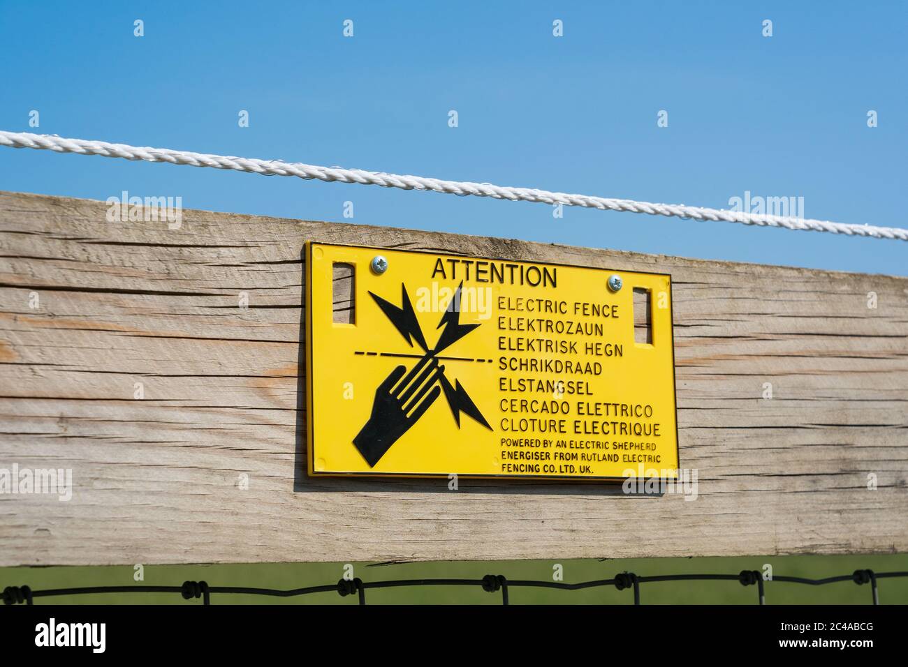 Sign on wooden fence warning people of electric fence. Green Tye, Much Hadham, Hertfordshire. UK Stock Photo