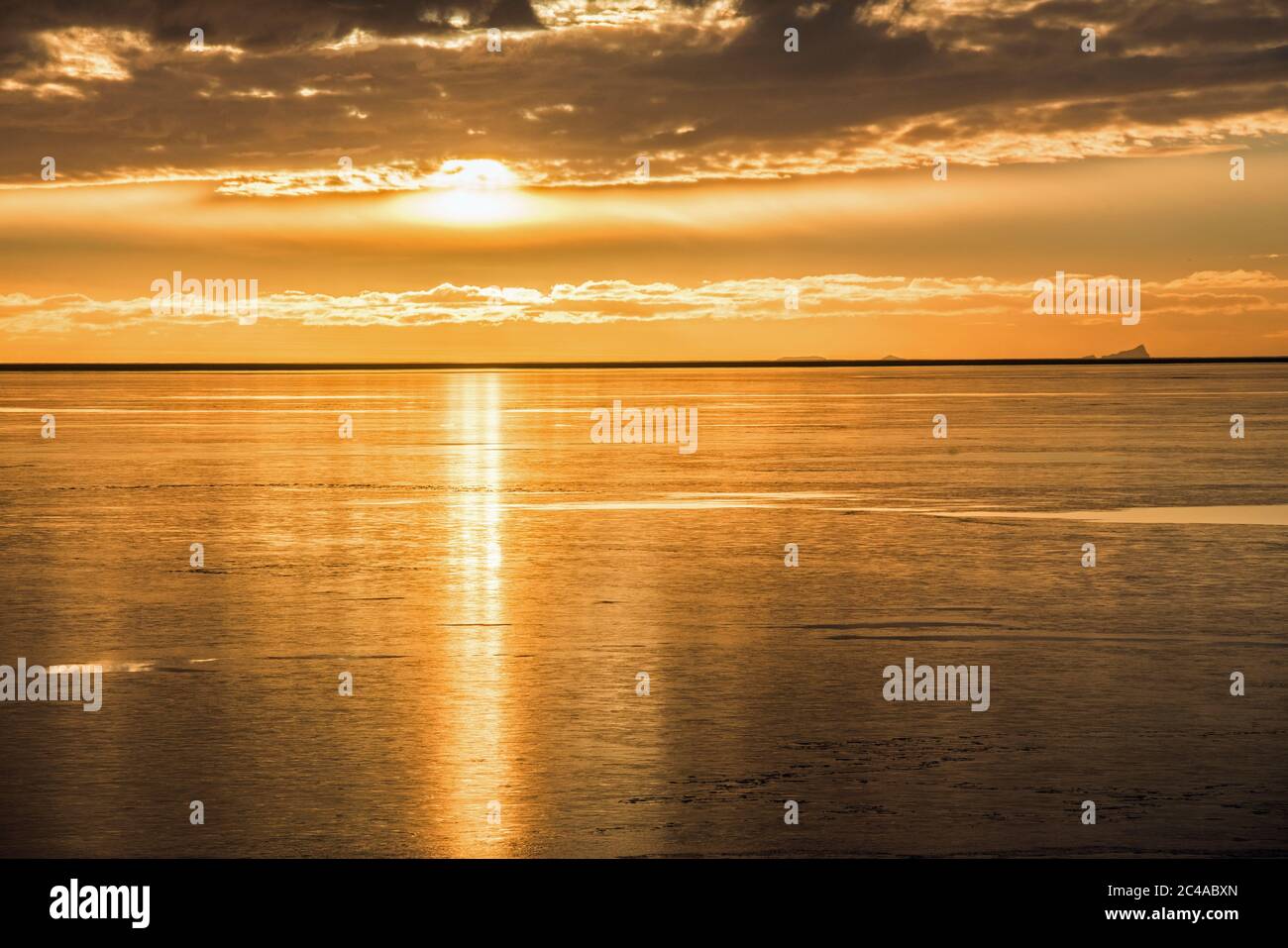 Vestmannaeyjar islands seen from near Landeyjahofn on the south Iceland coast. Photographed into the setting sun across the sea. Stock Photo