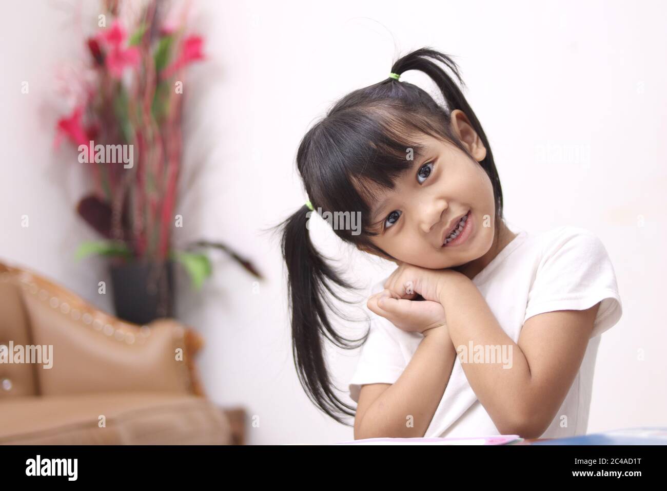 Cute adorable little Asian baby girl with pony tail hair looking at camera and smiling, happy joy excited expression when learning at home Stock Photo