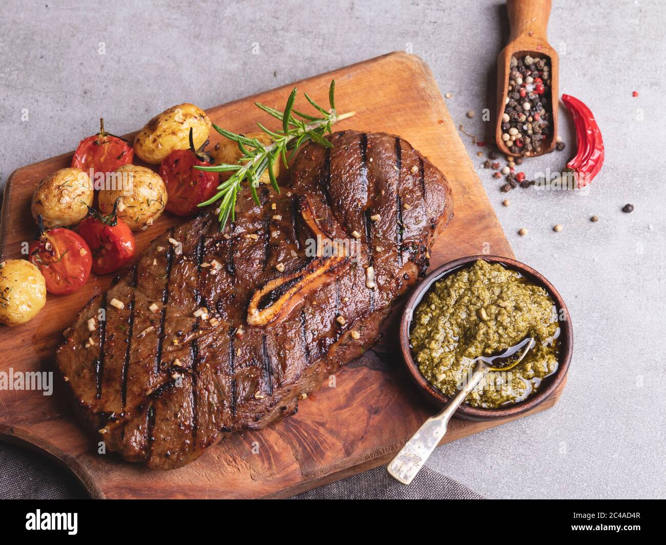 Juicy grilled beef steak with bone, potatoes, tomato wooden board sauce
