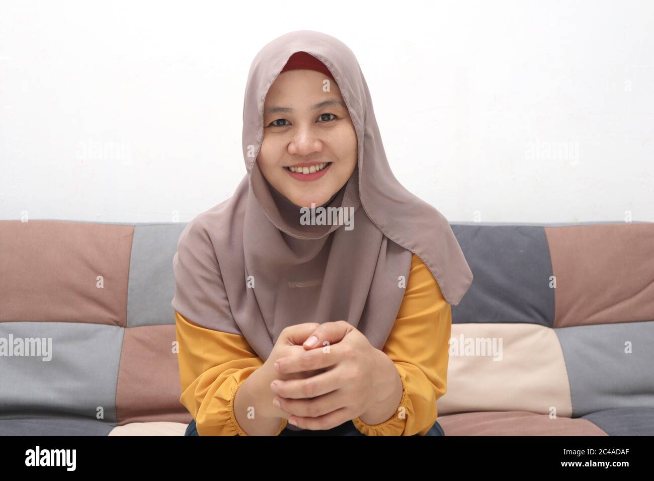 Beautiful Asian muslim lady doing selfie portrait on phone or doing video  call while sitting on sofa, happy smiling cheerful expression Stock Photo -  Alamy