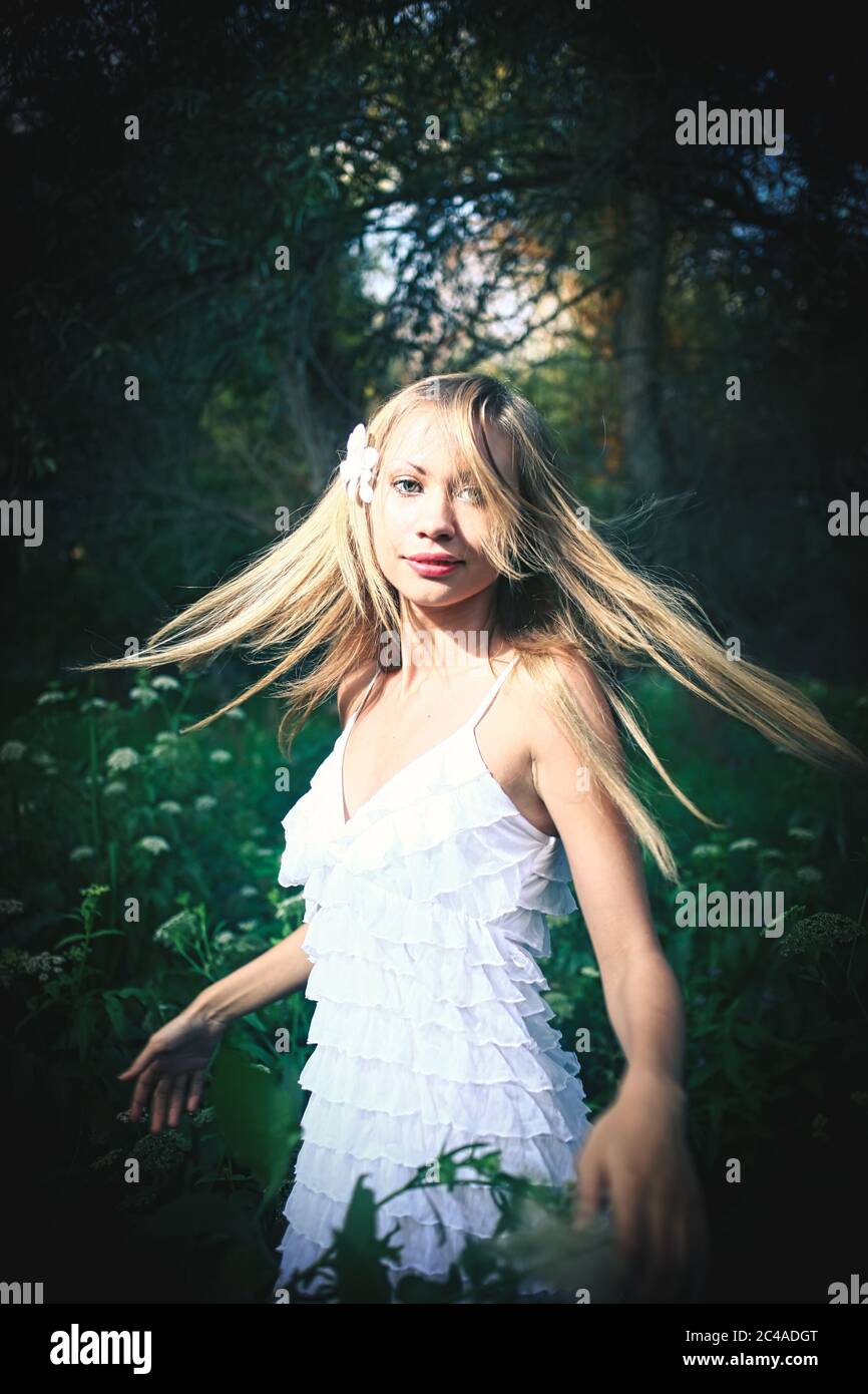 Fairy dancing in the forest. Pretty woman wearied white summer dress is  dancing with her hair flying in the air in woodland. Vintage looking image  Stock Photo - Alamy