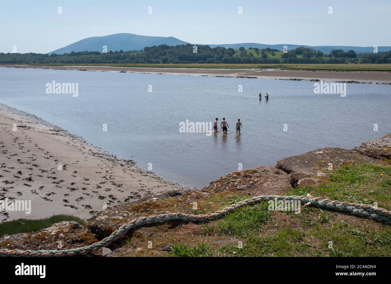 25th June, 2020, Glencaple, Scotland. People walk across the River Nith while the water level is low due to dry weather, taking a huge risk. Stock Photo