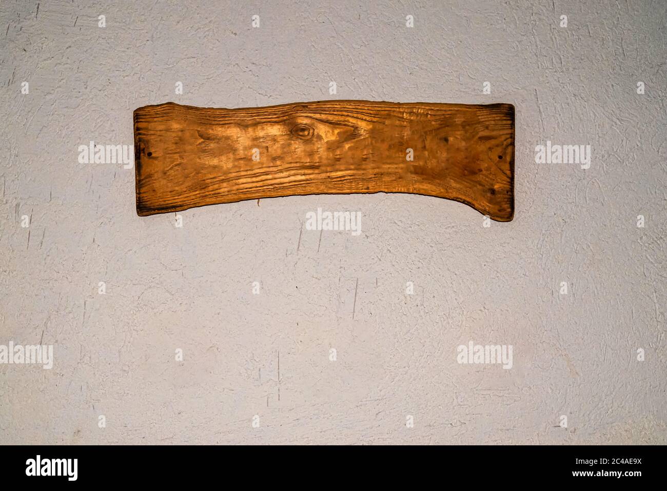 a blank wooden signboard on aged white rough texturized wall. Copy space. Stock Photo