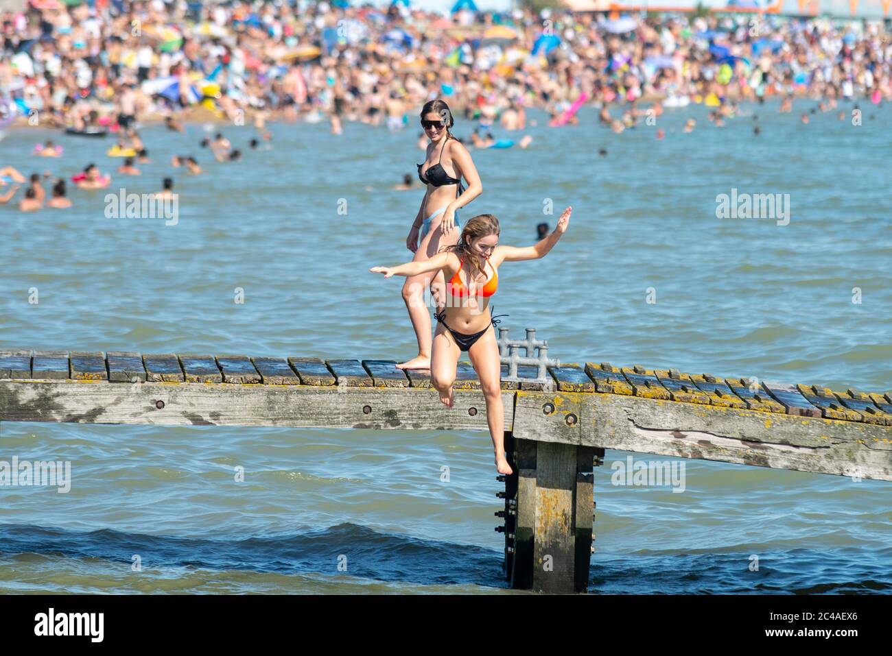 Southend on Sea, Essex, UK. 25th Jun, 2020. With the forecast record temperatures for 2020 people are heading to the seafront to cool down, despite the COVID-19 Coronavirus advice. In Southend on Sea the shore of the Thames Estuary is packed, with people swimming and jumping into the sea. Young white Caucasian female jumping into the sea Stock Photo