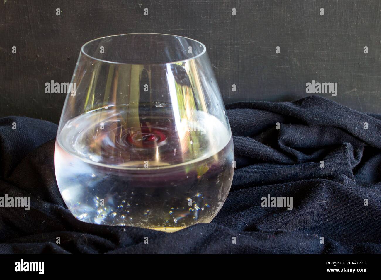A stirred Gin and Tonic, with a black background, garnished with pomegranate pits Stock Photo