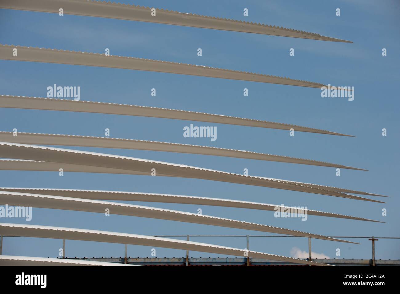 Glasgow, Scotland, UK. 25th June, 2020. Picture: Windmill turbine fan blades stacked in a holding depot in Govan in Glasgow. What is special about these fan blades is that they have a serrated trailing edge, which enables the reduction in aerofoil noise as the blade cuts through the air. Fan blades on large turbines normally reach speeds around 120 mph, causing noise. As the UK must meet its target for green energy renewables, technology will play a role in reducing the turbines noise footprint. Credit: Colin Fisher/Alamy Live News Stock Photo