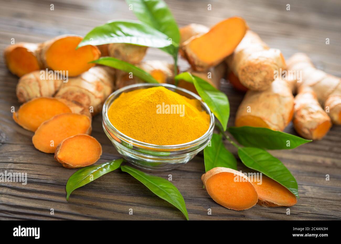 Turmeric powder and turmeric roots on the wooden table Stock Photo