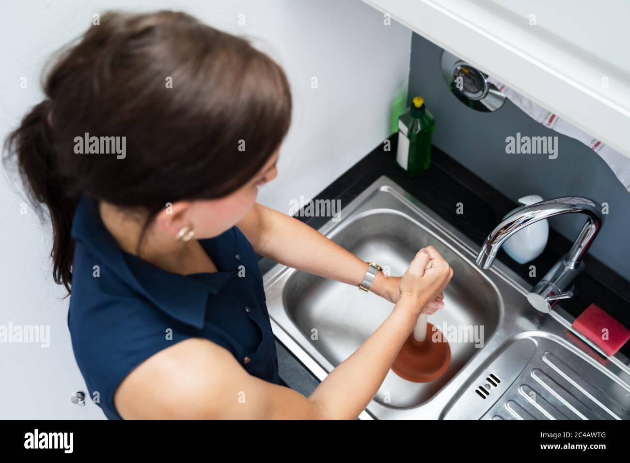 Cleaning Blocked Sink And Drain In Kitchen Using Plunger Stock Photo