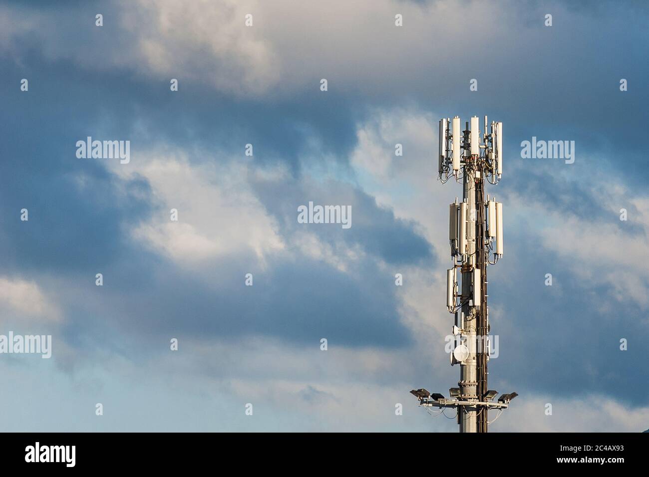 Electromagnetic radiation. Telecommunication tower with 5G and 4G antennas among clouds (with copy space) Stock Photo