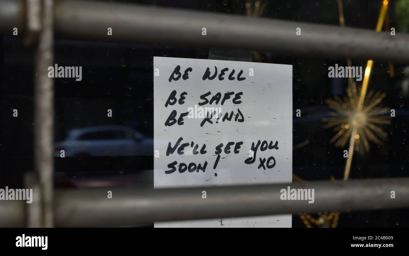 Handwritten sign in a shop window reading 'Be well be safe be kind we'll see you soon! xo', behind a security barrier gate, May 31, 2020, in New York. Stock Photo