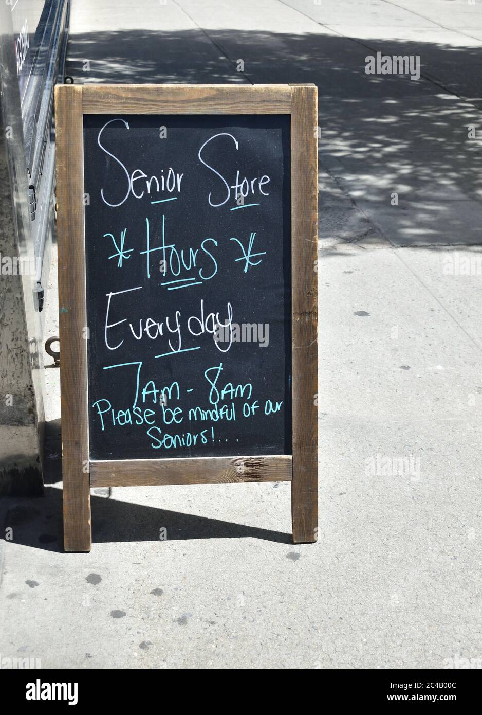 A-frame sign reading 'Senior store hours everyday - 7am to 8am. Please be mindful of our seniors!' on a city sidewalk, May 22, 2020, in New York. Stock Photo