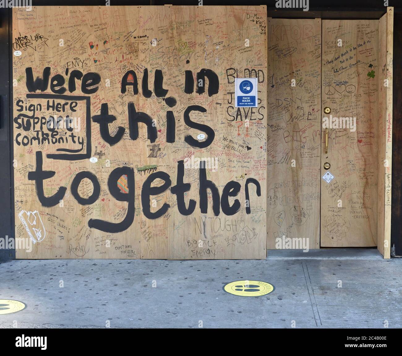 Plywood storefront with hand-painted message 'We're all in this together. Sign here support the community', May 14, 2020, in New York. Stock Photo