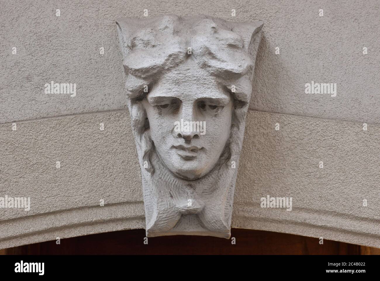Stone tympanum building feature of a downward-looking face on a curved arch over a doorway, Feb. 22, 2020, in New York. Stock Photo