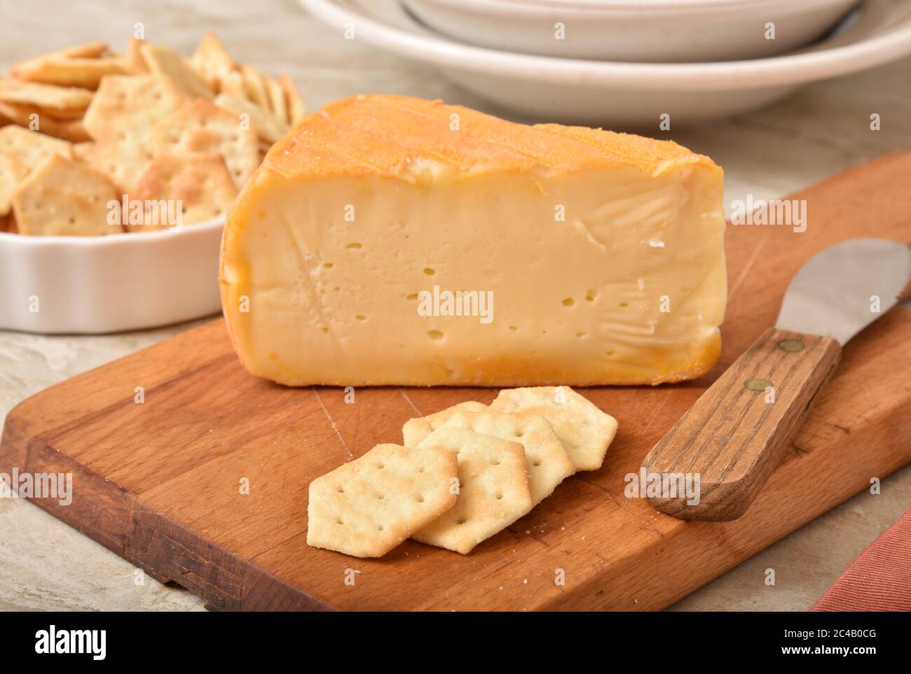 A wedge of imported Belgium Autumn Cheese with artisan crackers. Focus on crackers Stock Photo
