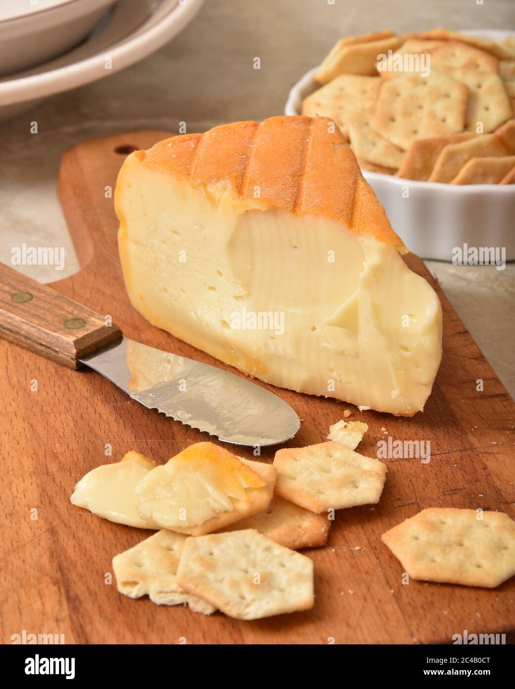 A wedge of goumet imported Belgium Autumn Cheese with artisan crackers. Focus on cheese wedge Stock Photo