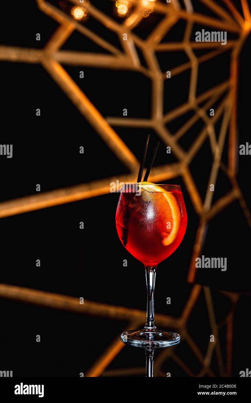 Aperol spritz cocktail in a wine glass, ice, slice of orange, straw, on black table Stock Photo