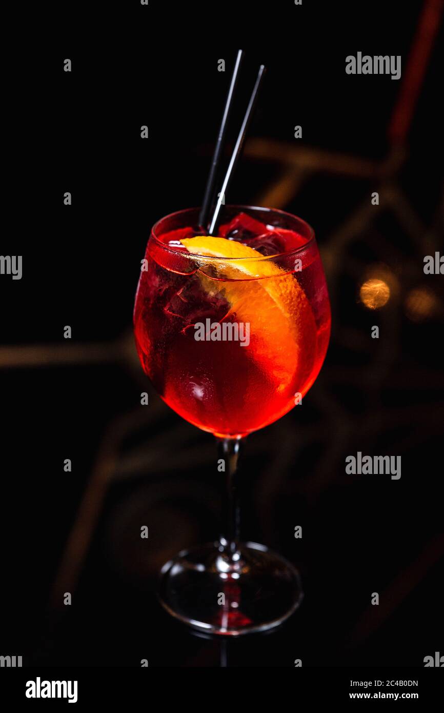 Aperol spritz cocktail in a wine glass, ice, slice of orange, straw, on black table Stock Photo