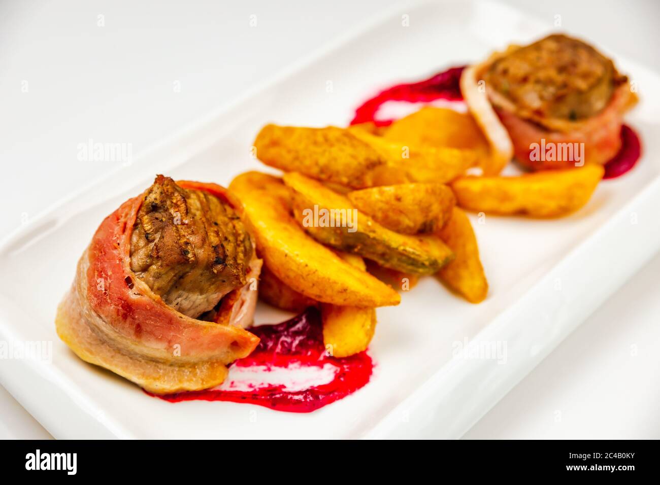 Fillet mignon rolled in bacon and baked in oven with berry sauce. Potato for garnish. Stock Photo