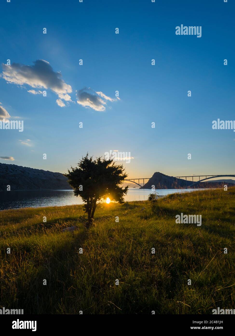 Sunset landscape silhouette silhouetting trees bridge mainland to island Krk Croatia Stock Photo