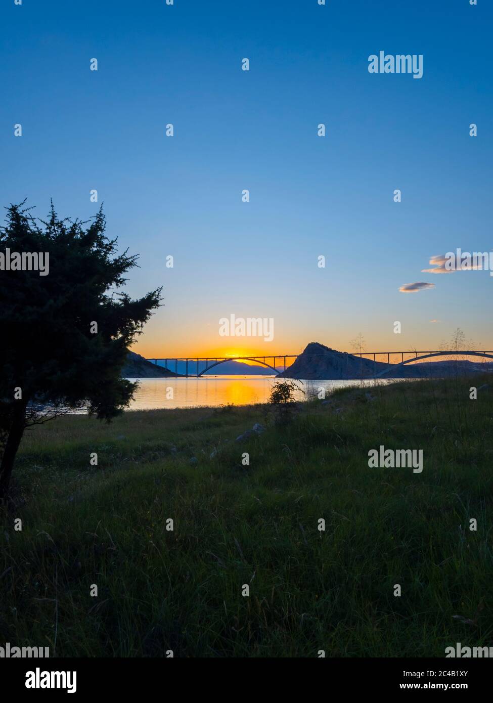 Sunset landscape silhouette silhouetting trees bridge mainland to island Krk Croatia Stock Photo