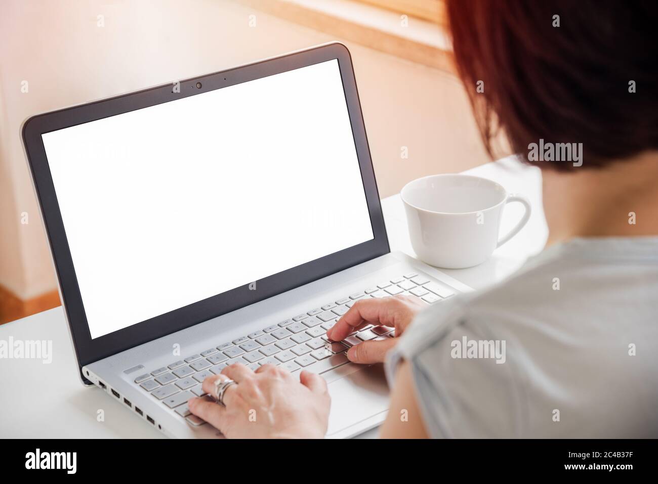 Woman working on a laptop at home. Blank monitor. Working from home