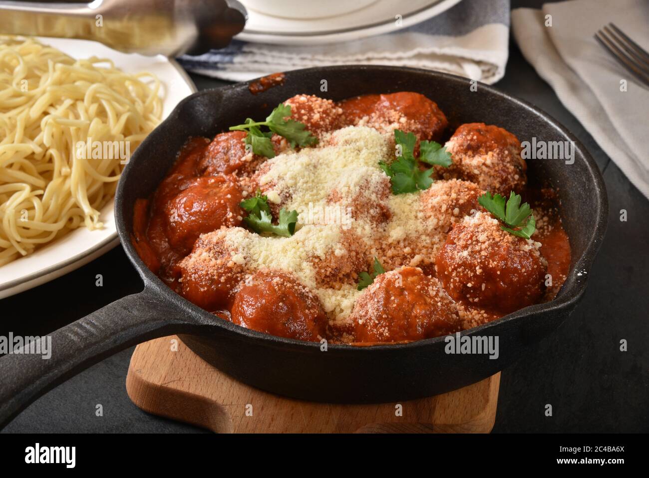 A cast iron skillet with Italian meatballs and marinara sauce with