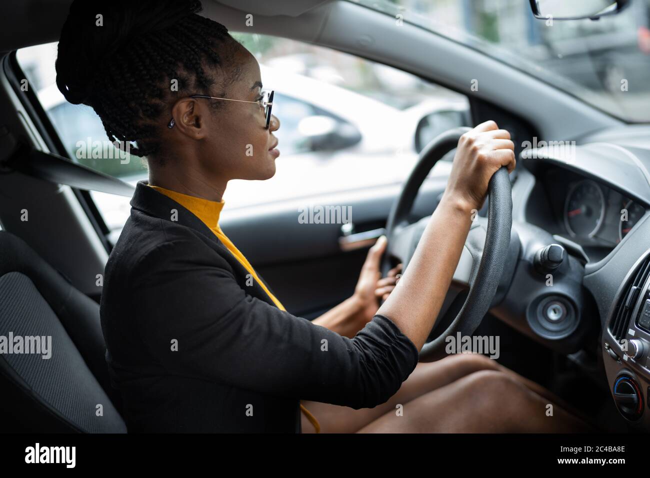 African Woman Holding Steering Wheel While Driving Car Stock Photo