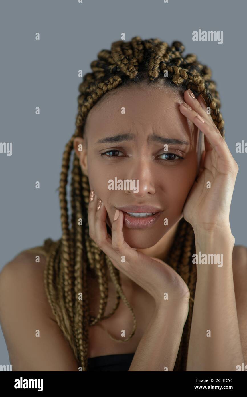 Devastated young African American holding her face with her hands, frowning with pain Stock Photo