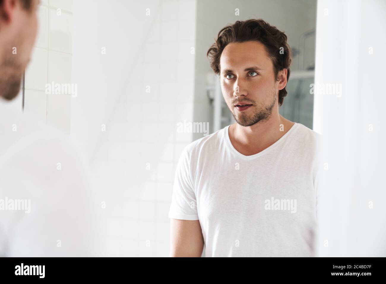 Man In The Bathroom Looking At Himself In The Mirror Hi Res Stock