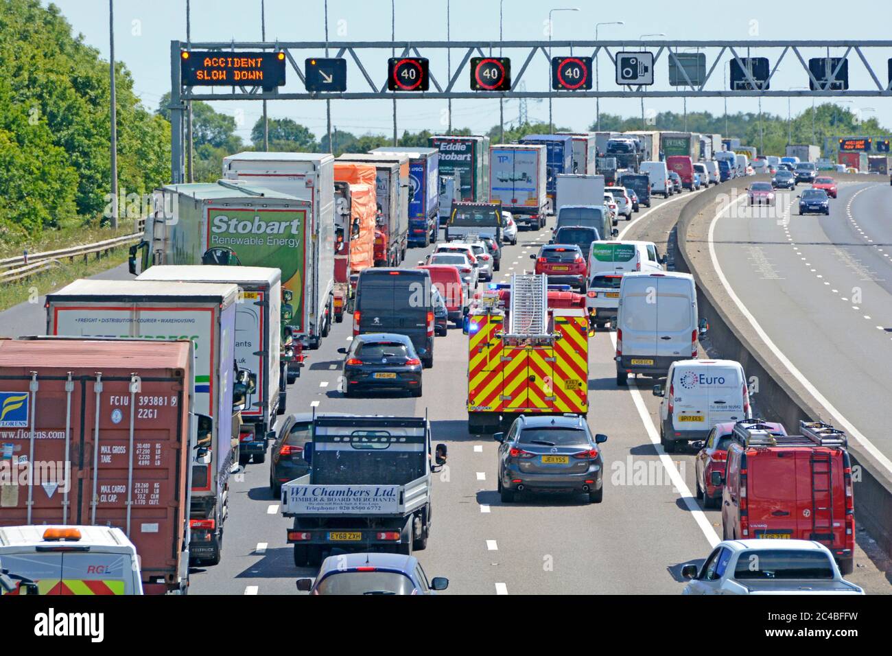 Motorway gridlock traffic jam & fire engine on emergency services call to reach scene of accident near Brentwood as shown on m25 gantry road sign UK Stock Photo