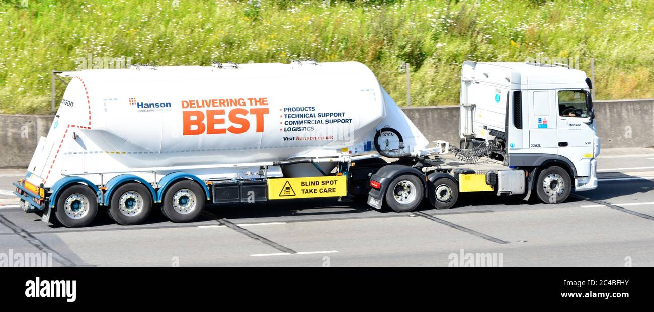 Logo & advertising on side of Hanson Heidelberg bulk cement supply chain business group tanker trailer blind spot & hgv lorry truck on UK M25 motorway Stock Photo