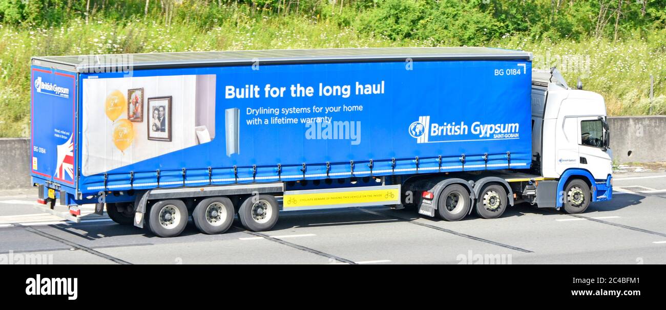 Side view British Gypsum Saint-Gobain plasterboard drylining business company supply chain lorry truck & trailer transport with brand advertising UK Stock Photo