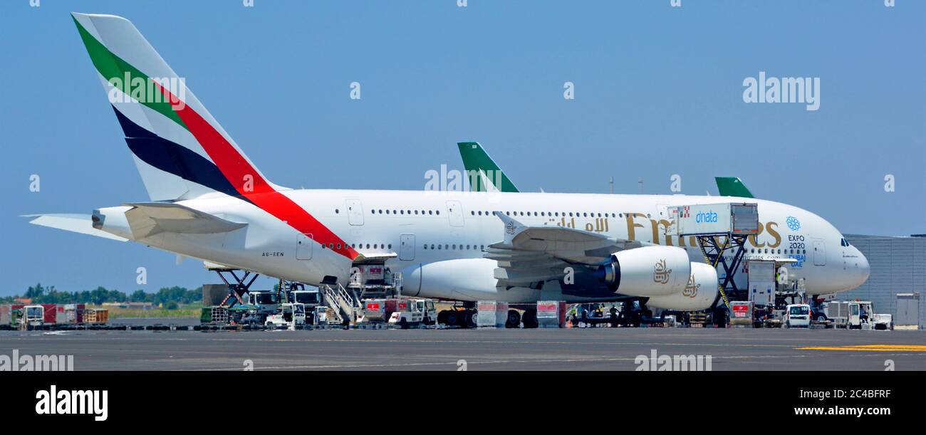 Emirates logo on Airbus A380 double deck wide body four engine jet airplane airport apron stand ground crew in attendance Rome Fiumicino Airport Italy Stock Photo