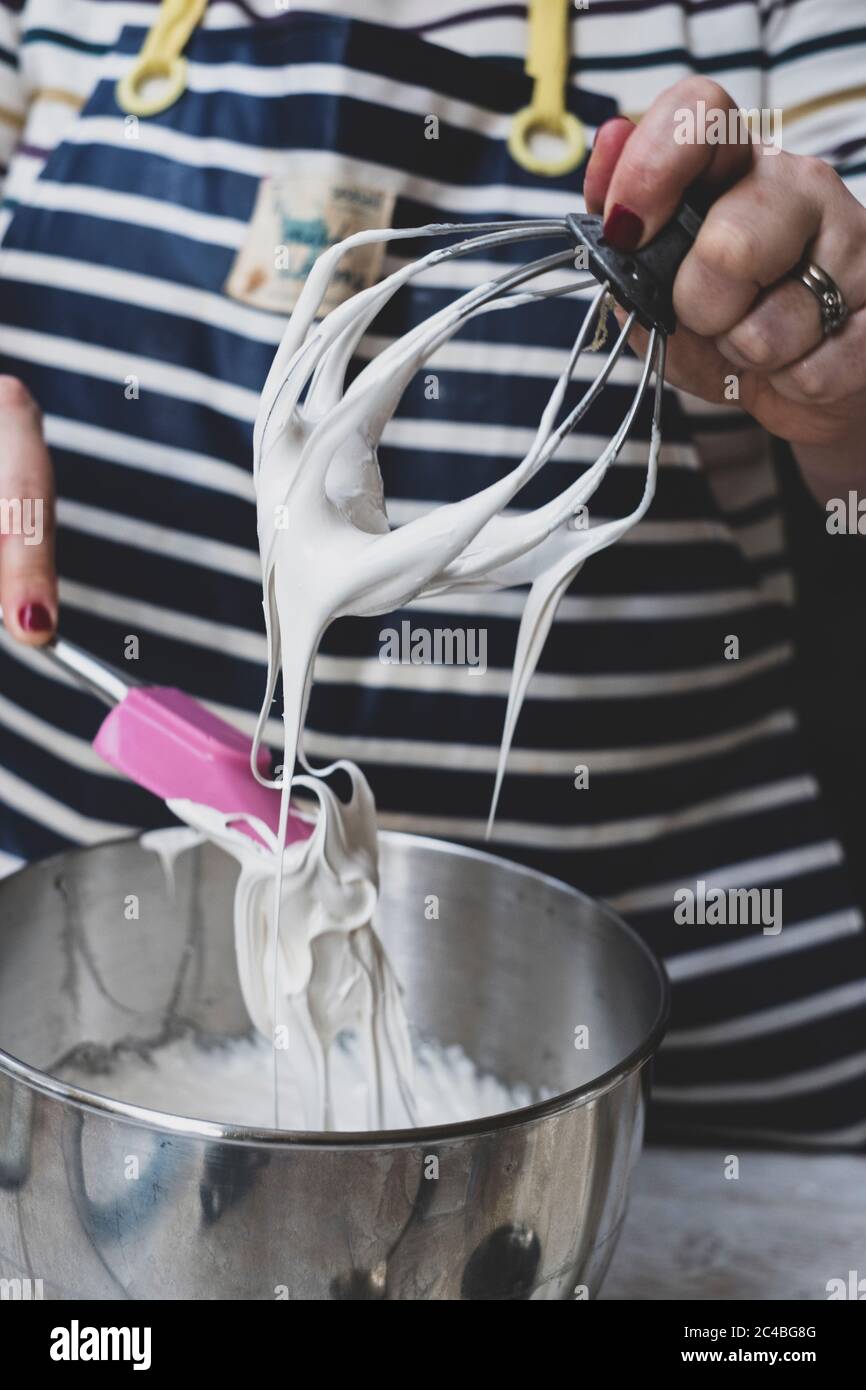A woman making meringues whipping egg whites iwth a  whisk. Stock Photo