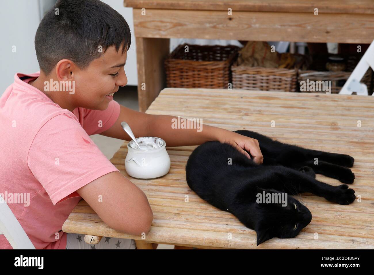 Smiling boy stroking a black cat in salento, italy Stock Photo