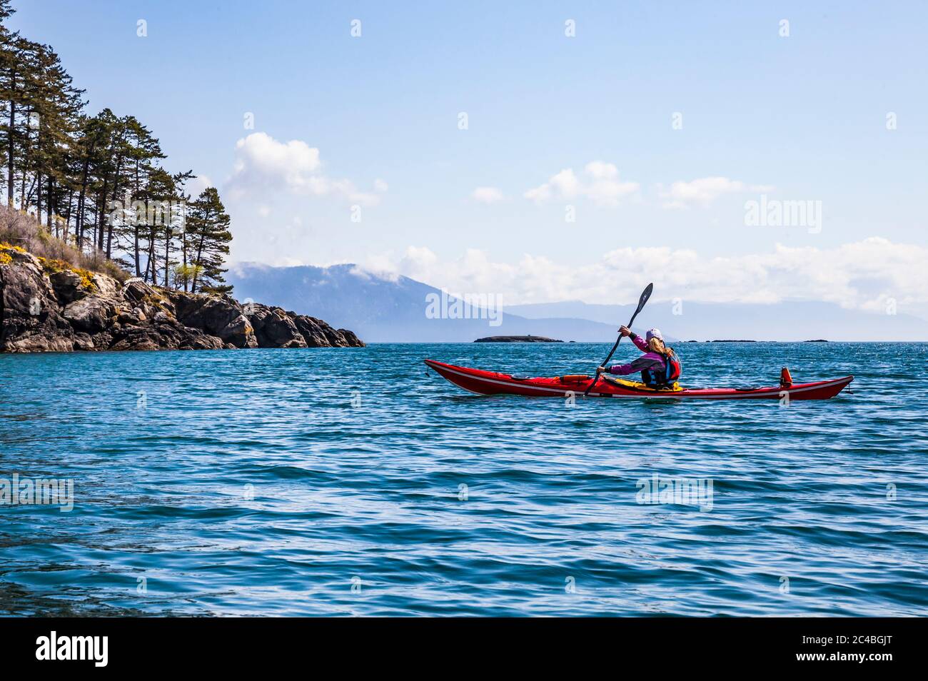 A woman sea kayaking in the morning off of Orcas Island in Rosario