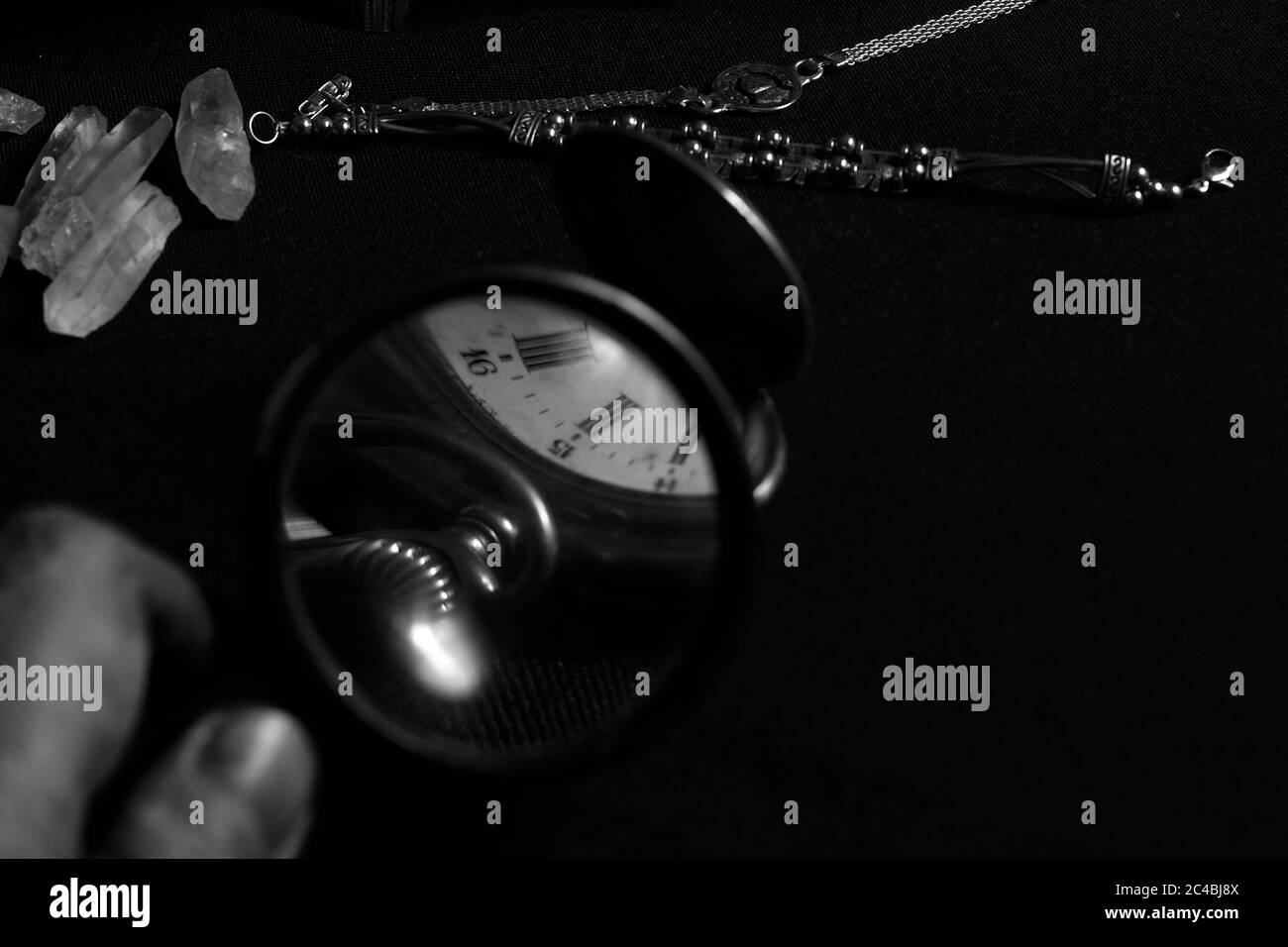 Magnifying glass with an old pocket watch in black and white Stock